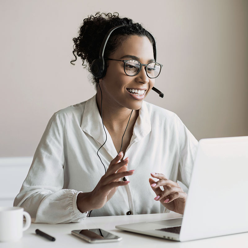 Woman wearing a headset and chatting in front of a laptop