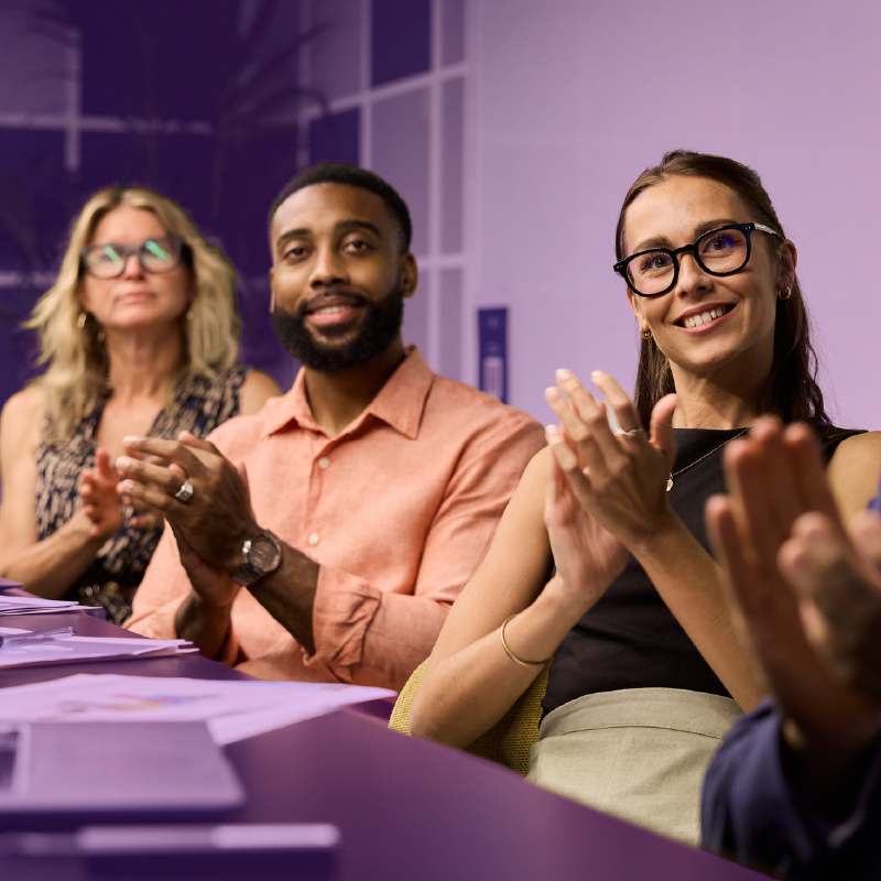 Group of colleagues sitting at a conference table and applauding during a meeting