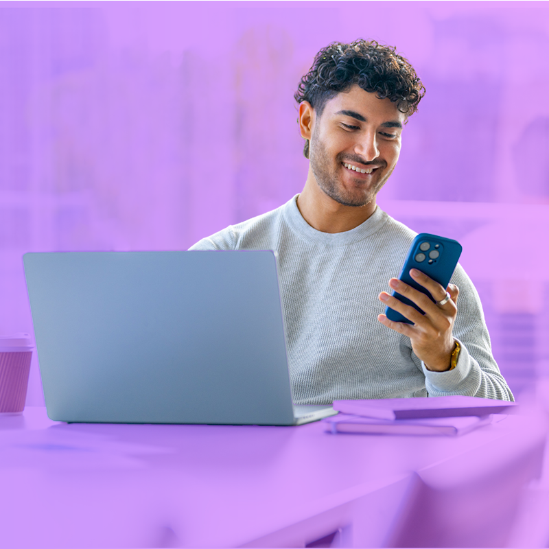 Man working in front of laptop while using a phone