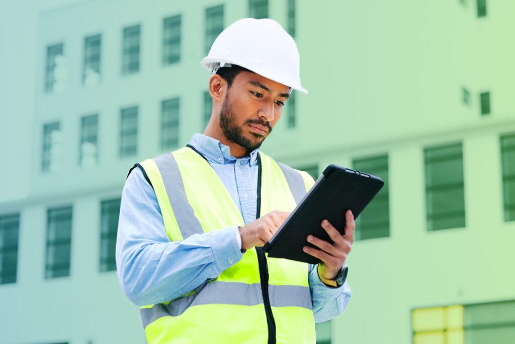 Smiling man holding a tablet on a worksite