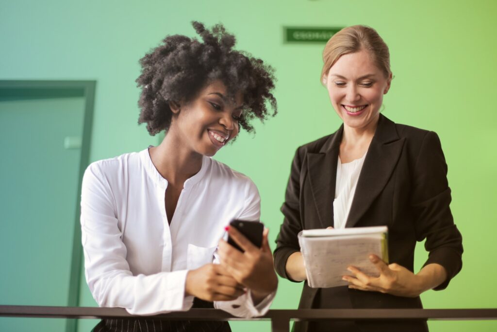 Two colleagues chatting while one holds a notebook