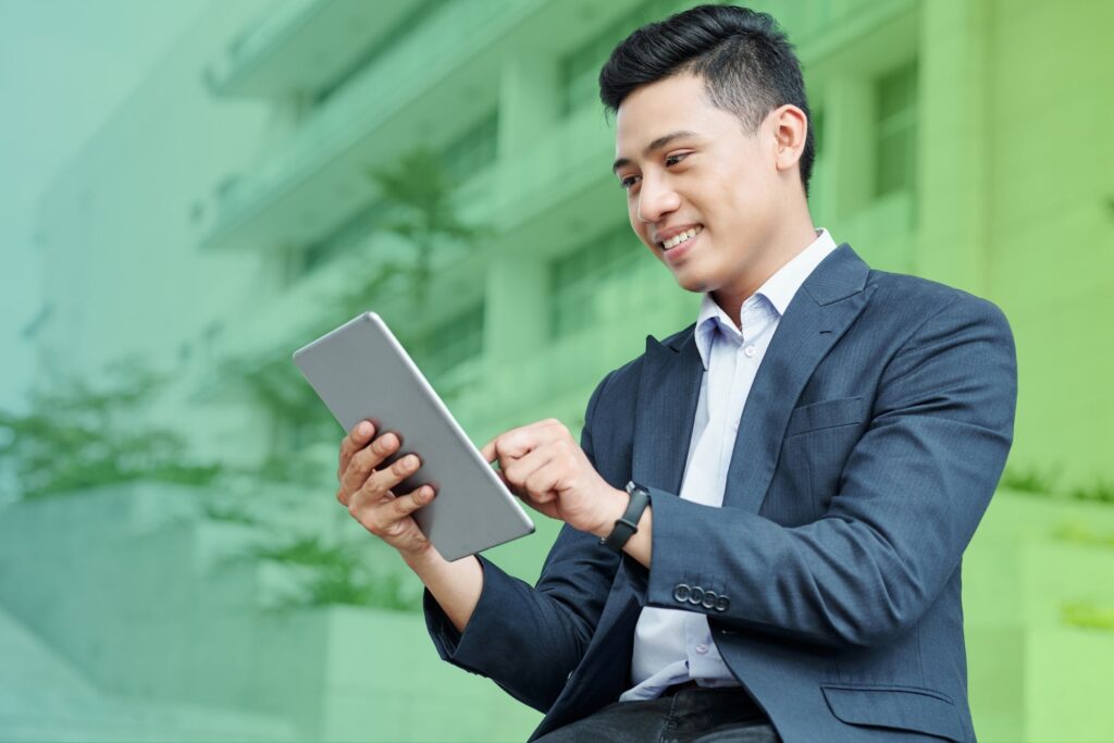 Smiling man holding a tablet outside an office