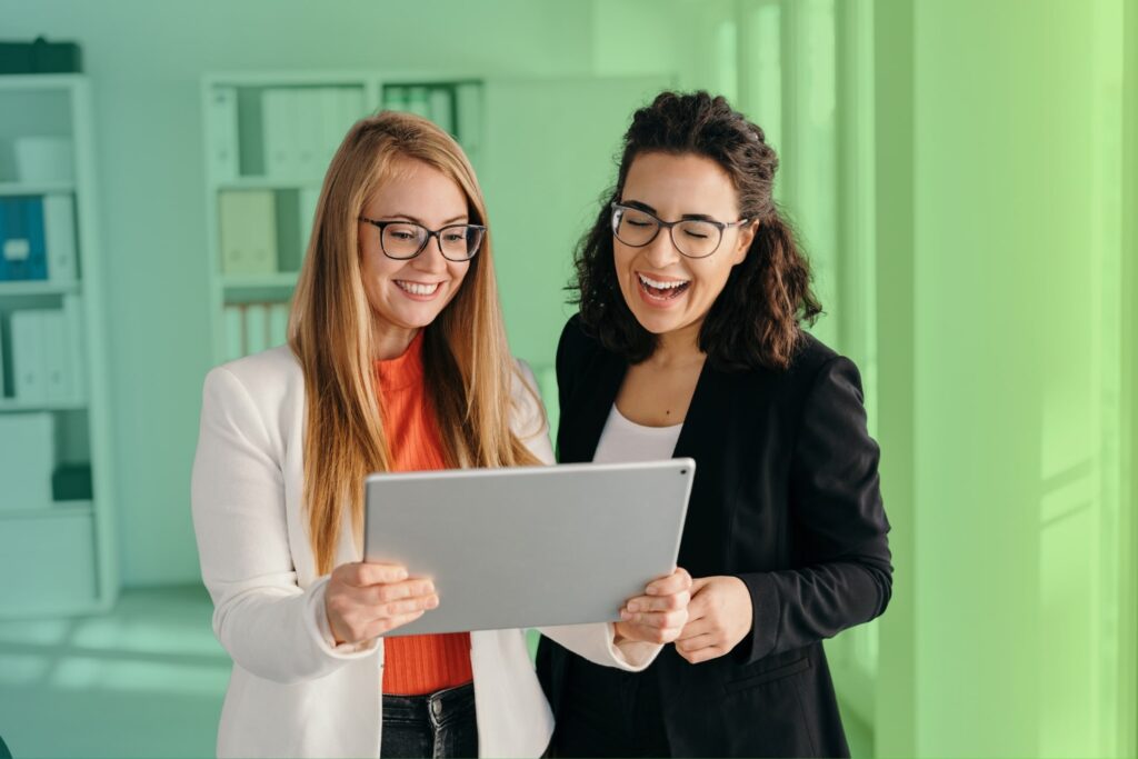 Two colleagues chatting while one holds a tablet