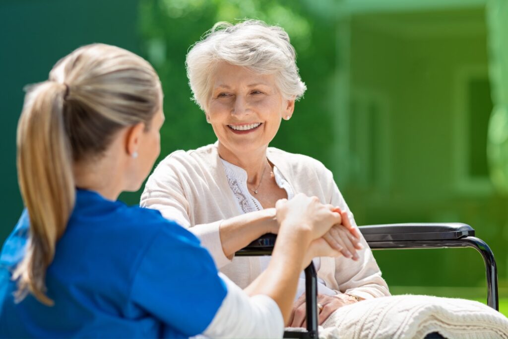 A senior woman smiling while talking with a caregiver outdoors