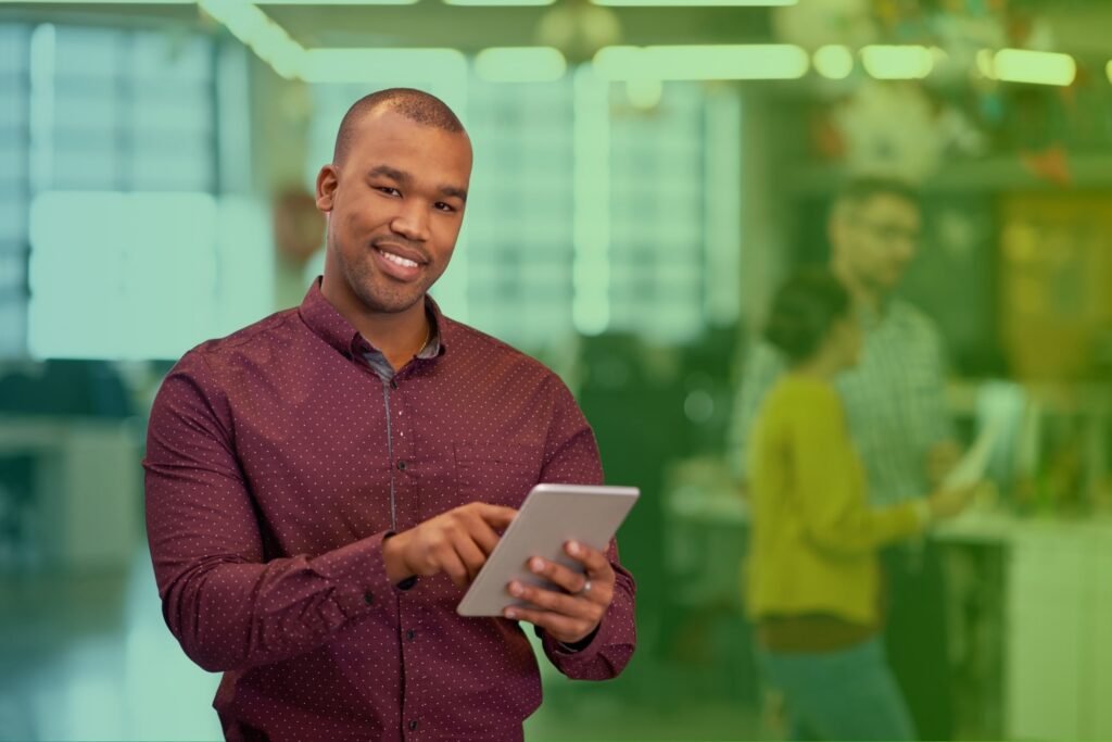 Smiling man holding a tablet in an office setting