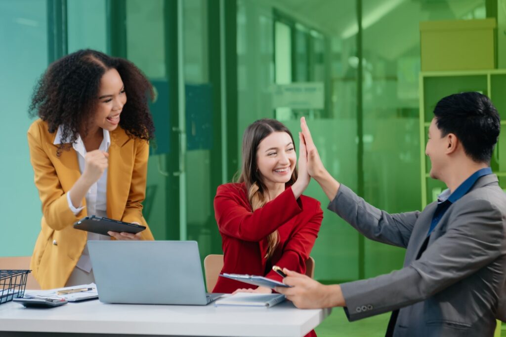 Three colleagues chatting in front of a laptop