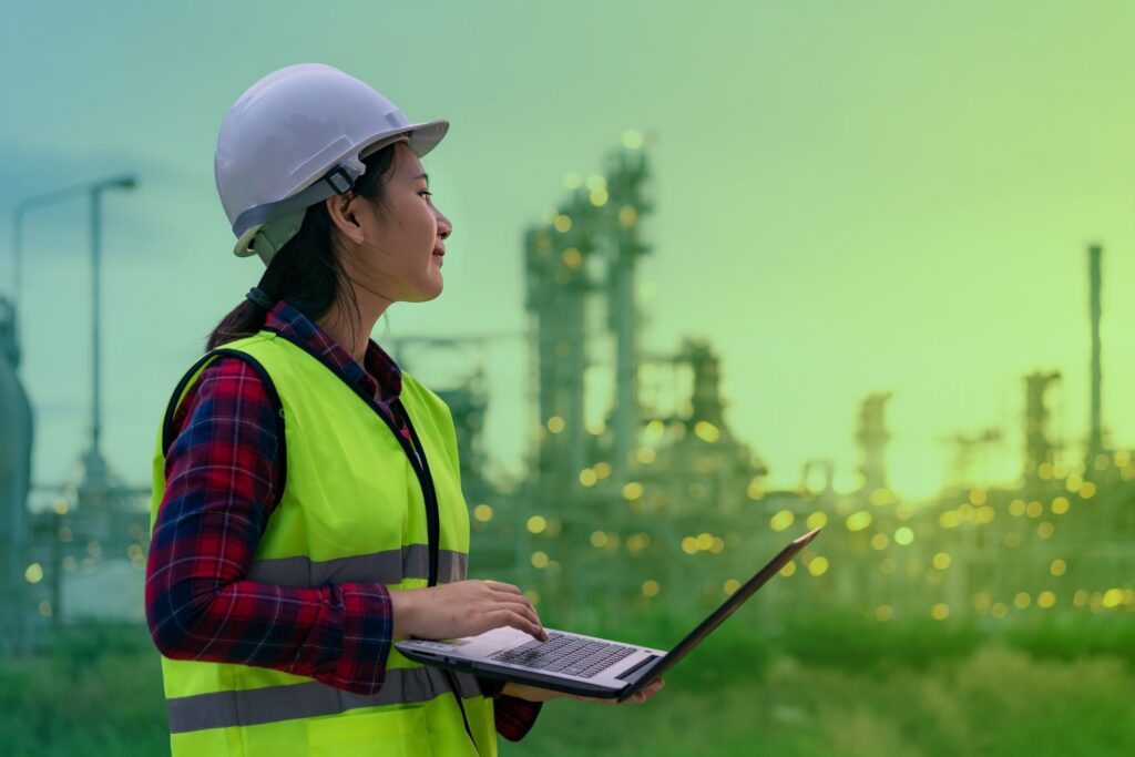 Woman in a hard hat taking notes on a laptop