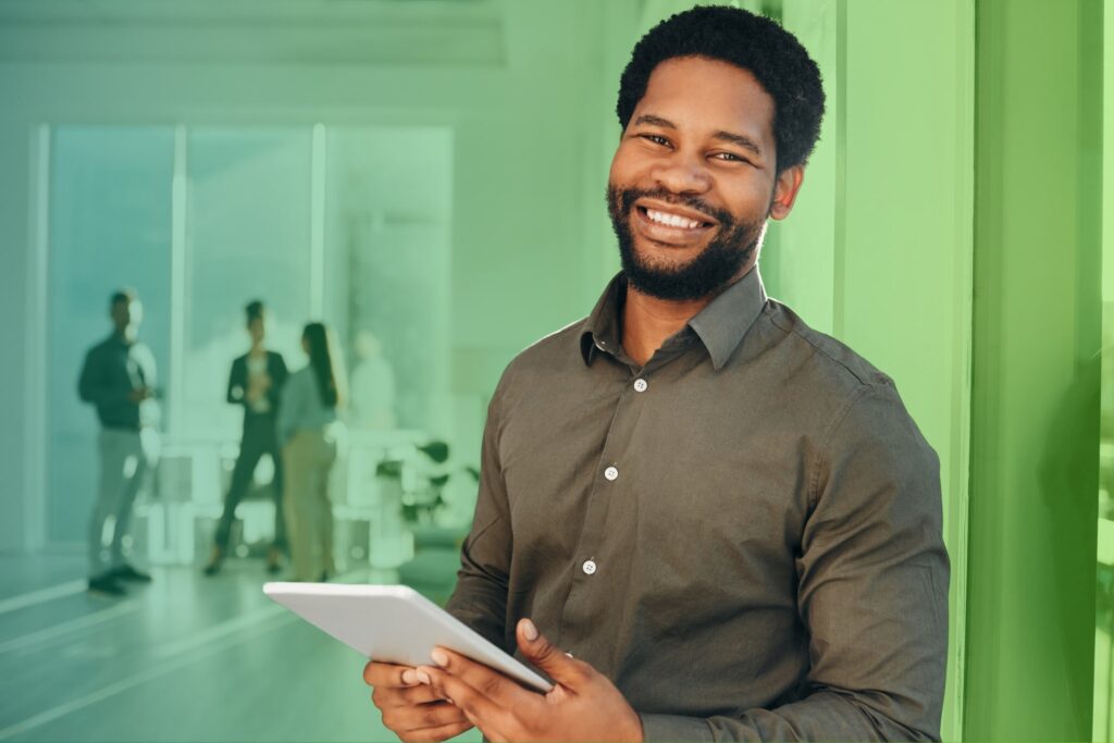 Smiling man holding a tablet in an office setting