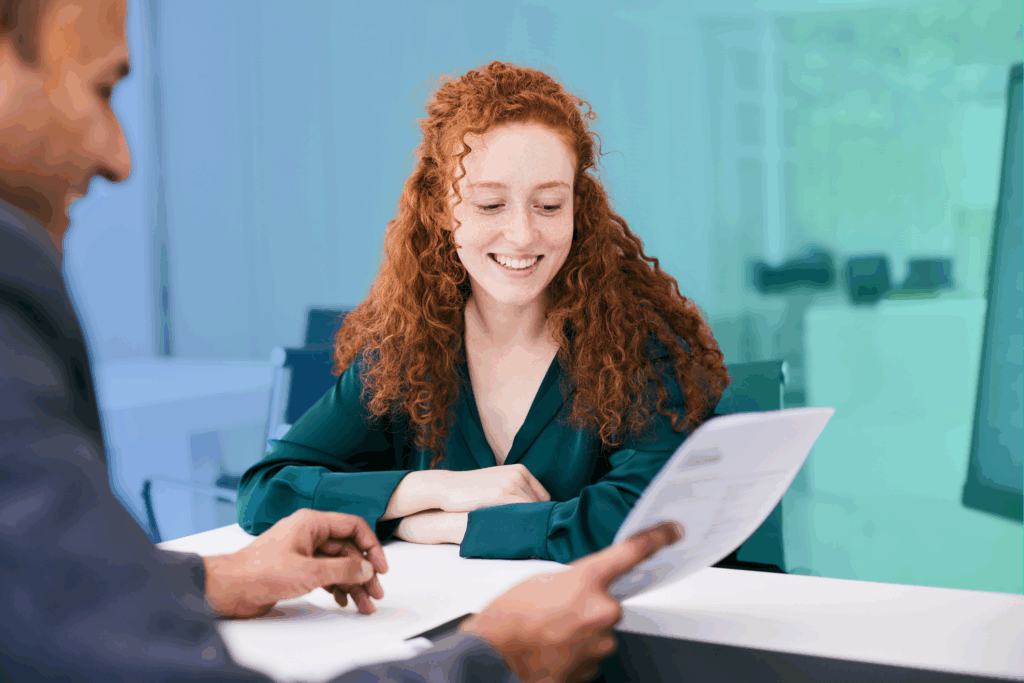 Smiling woman reviews a document during a meeting across a desk