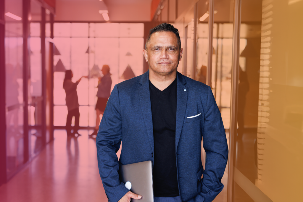 Businessman holding a laptop while standing in an office hallway